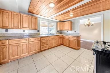 kitchen with light tile patterned floors, wood ceiling, a sink, and an inviting chandelier