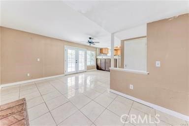 unfurnished living room with french doors, light tile patterned flooring, and baseboards