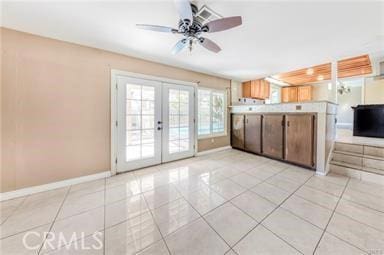 kitchen with light tile patterned floors, baseboards, ceiling fan, light countertops, and french doors