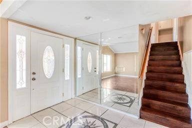 entrance foyer with lofted ceiling, light tile patterned floors, and stairs