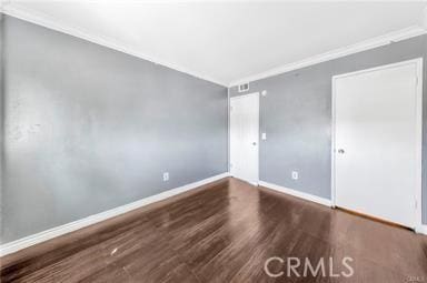 spare room with baseboards, wood finished floors, and ornamental molding