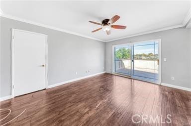 empty room with ornamental molding, wood finished floors, and baseboards