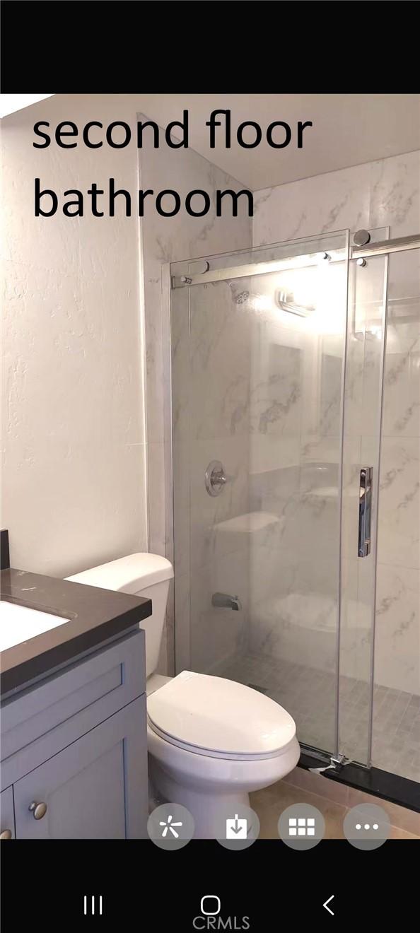 bathroom with a stall shower, vanity, and toilet