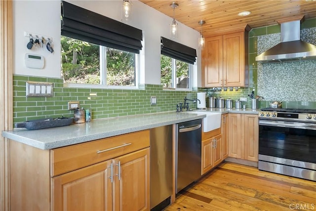 kitchen with a sink, stainless steel appliances, wall chimney exhaust hood, light wood finished floors, and wood ceiling