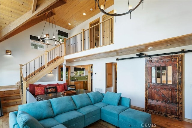 living area featuring a chandelier, a barn door, and wood finished floors