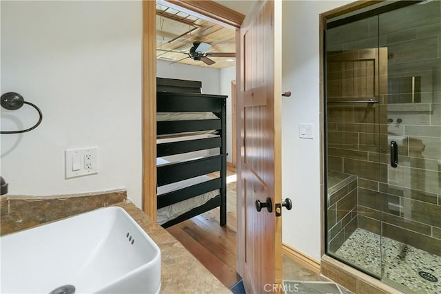 bathroom featuring a sink, wood finished floors, a shower stall, and a ceiling fan