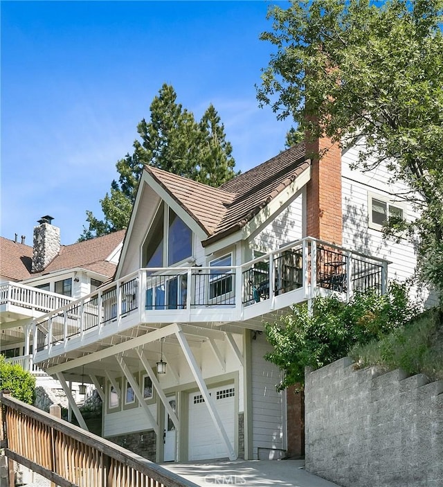 rear view of house featuring a garage, driveway, and a chimney