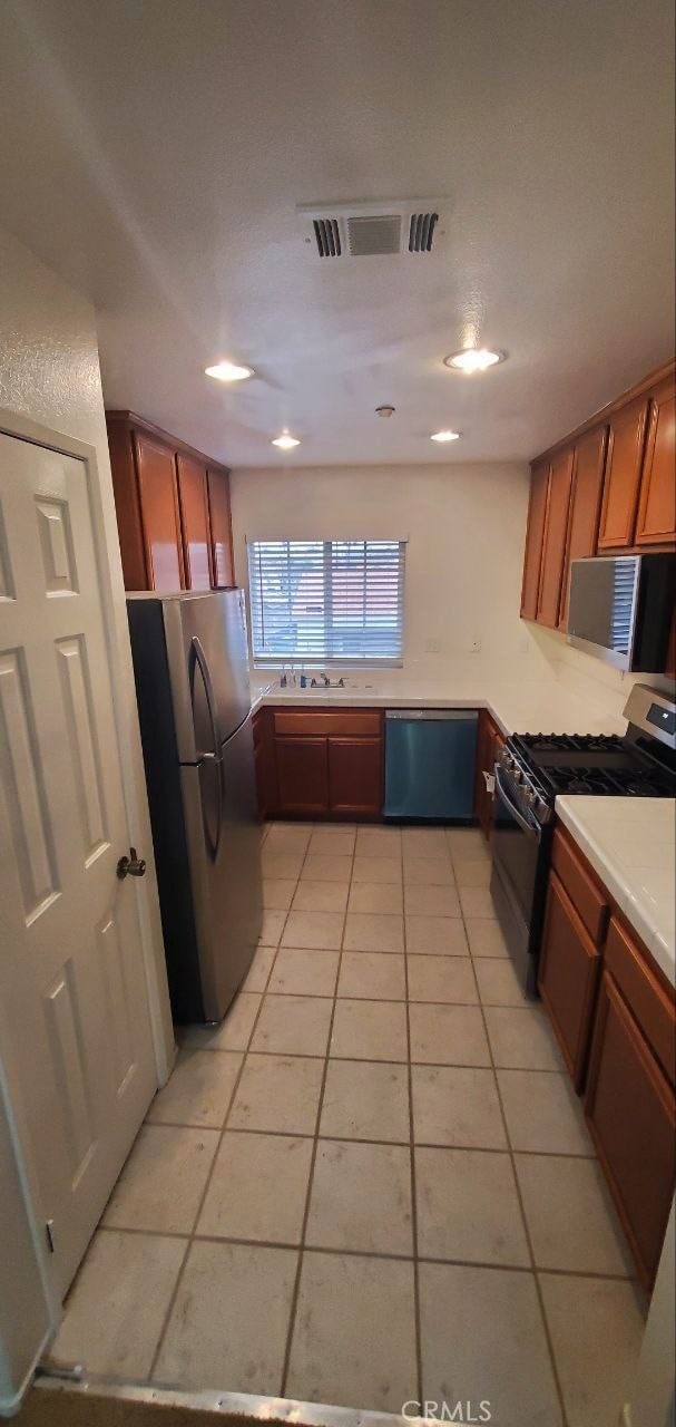 kitchen featuring visible vents, brown cabinets, stainless steel appliances, light countertops, and light tile patterned floors