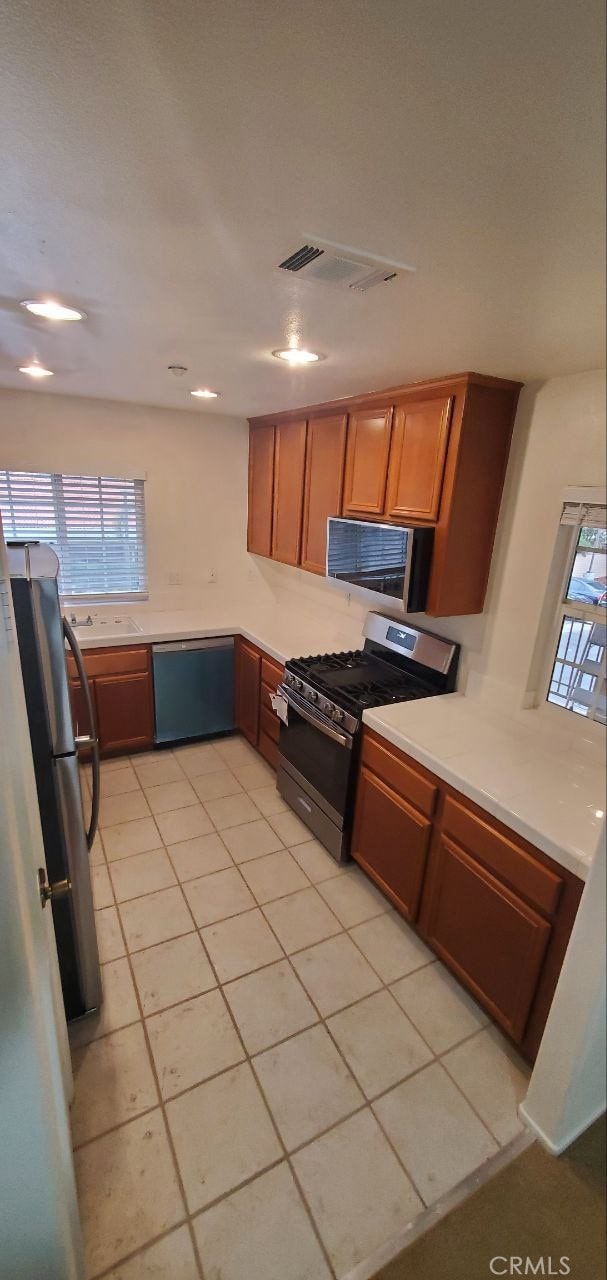 kitchen featuring visible vents, a sink, light countertops, appliances with stainless steel finishes, and brown cabinets