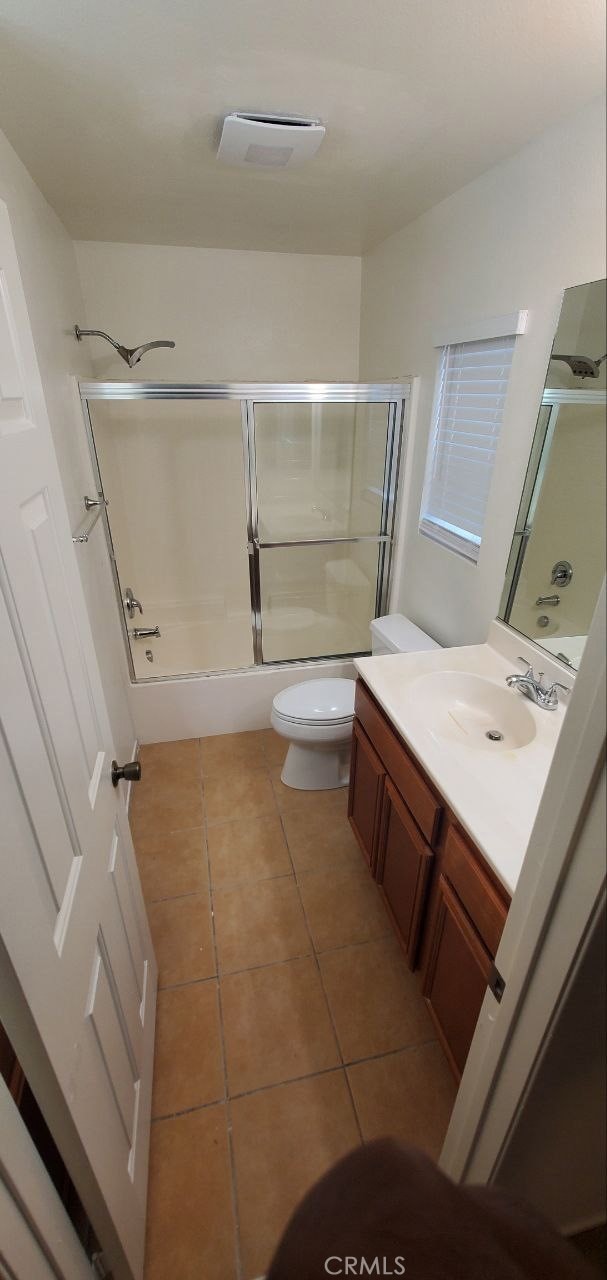 bathroom featuring vanity, visible vents, shower / bath combination with glass door, tile patterned flooring, and toilet