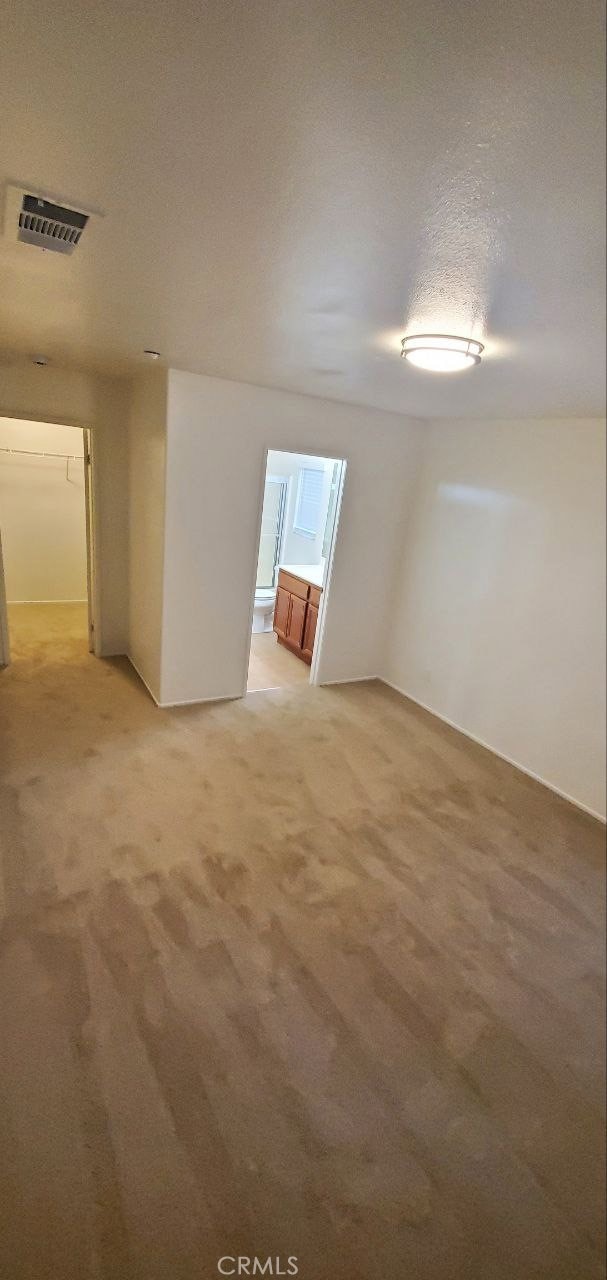 unfurnished room featuring light colored carpet, visible vents, and a textured ceiling