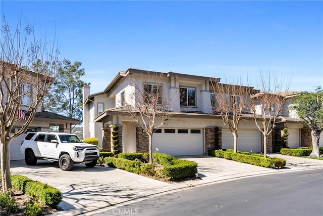 view of front of house featuring an attached garage, stone siding, driveway, and stucco siding