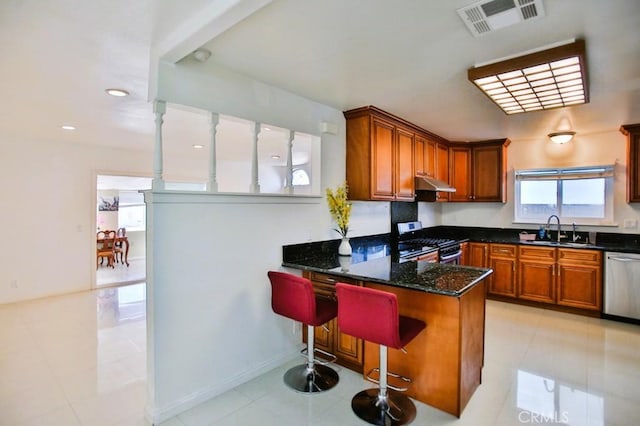 kitchen with stainless steel appliances, visible vents, a sink, a peninsula, and under cabinet range hood