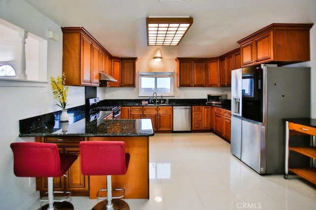 kitchen with a peninsula, appliances with stainless steel finishes, brown cabinets, and a sink