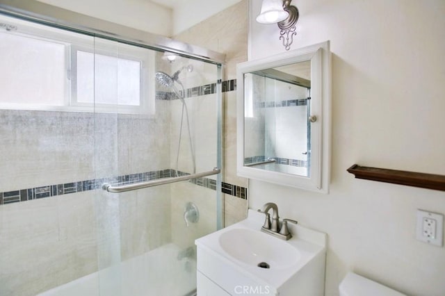 full bath with vanity, a tile shower, and toilet