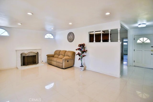 living area featuring a healthy amount of sunlight, a premium fireplace, baseboards, and recessed lighting