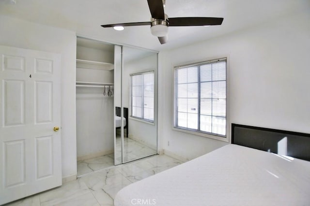 bedroom featuring marble finish floor, ceiling fan, baseboards, and a closet