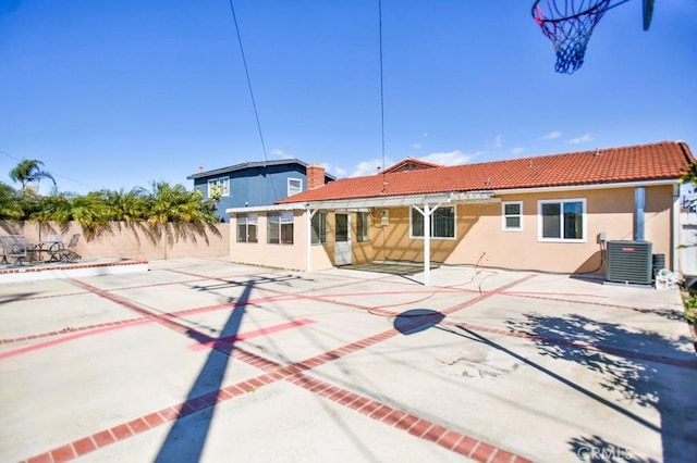 back of property with central AC unit, a tile roof, fence, and stucco siding