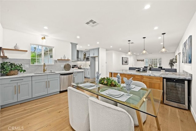 kitchen featuring visible vents, gray cabinetry, a sink, stainless steel dishwasher, and wine cooler