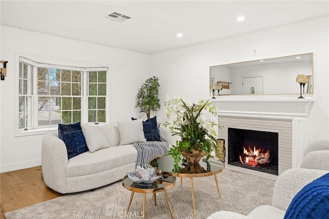 living room with wood finished floors, visible vents, baseboards, a fireplace, and recessed lighting