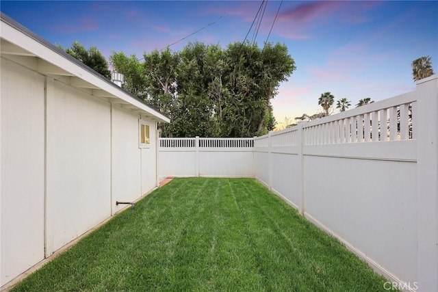 yard at dusk featuring a fenced backyard