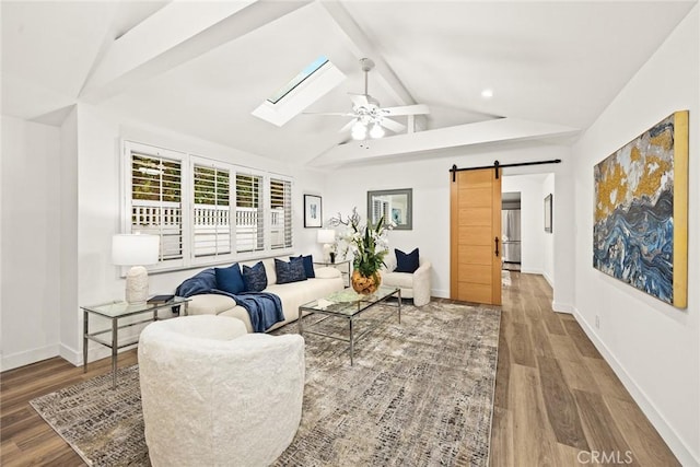 living area with a barn door, vaulted ceiling with skylight, wood finished floors, and baseboards