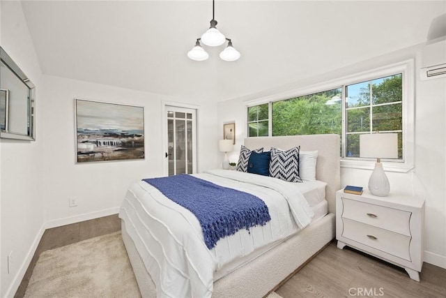 bedroom featuring an AC wall unit, wood finished floors, and baseboards