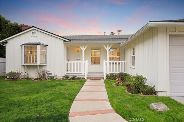 view of front of home featuring board and batten siding, a garage, a lawn, and covered porch