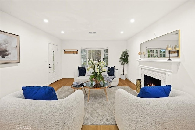 living room with a fireplace with flush hearth, recessed lighting, baseboards, and wood finished floors