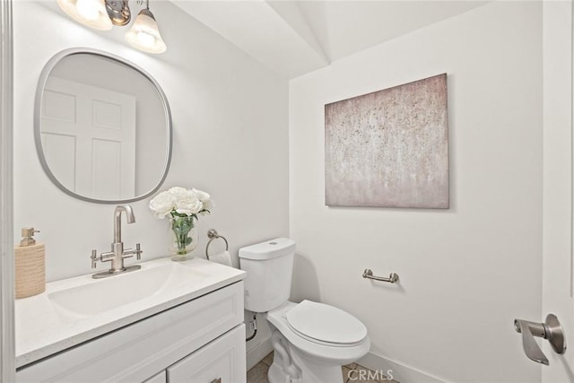 bathroom with toilet, vanity, and baseboards