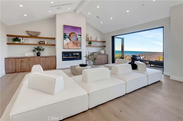 living area featuring baseboards, a glass covered fireplace, light wood-style floors, high vaulted ceiling, and beam ceiling