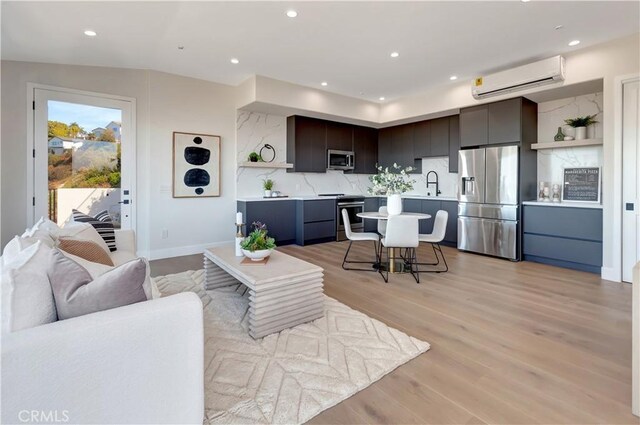 living area with recessed lighting, light wood-style flooring, baseboards, and a wall mounted AC