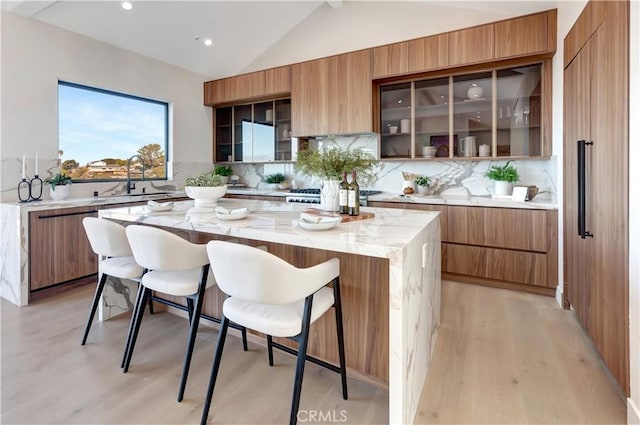 kitchen with a breakfast bar area, lofted ceiling, decorative backsplash, a kitchen island, and modern cabinets