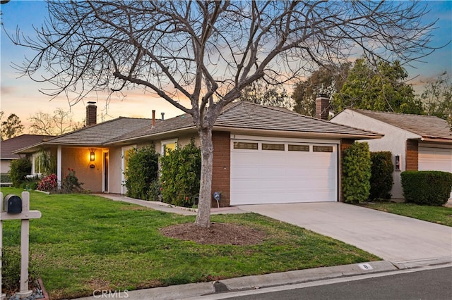 ranch-style house with an attached garage, driveway, a chimney, and a lawn