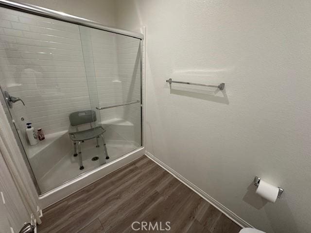 bathroom featuring a shower with door and wood finished floors