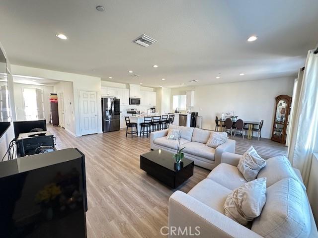 living room featuring recessed lighting, light wood-style floors, and visible vents