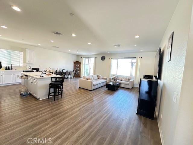 living room with recessed lighting, wood finished floors, and visible vents