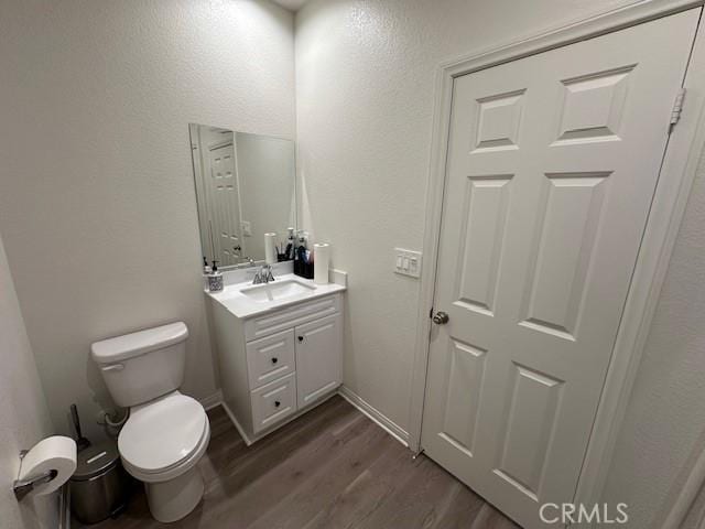 bathroom featuring vanity, toilet, wood finished floors, and baseboards