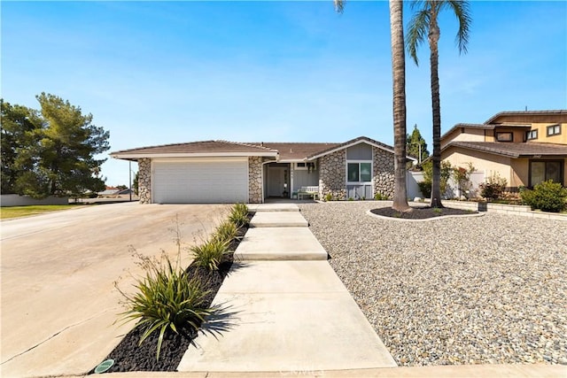 view of front of house with an attached garage, stone siding, and driveway