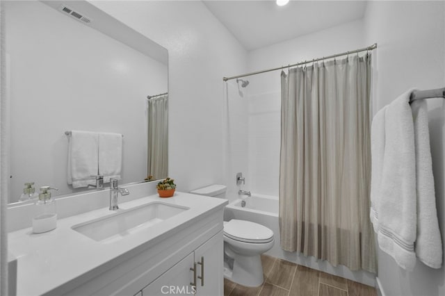 bathroom featuring wood finish floors, visible vents, toilet, shower / bath combo with shower curtain, and vanity