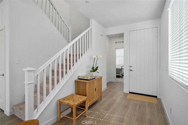 entryway featuring stairs, wood finished floors, visible vents, and baseboards