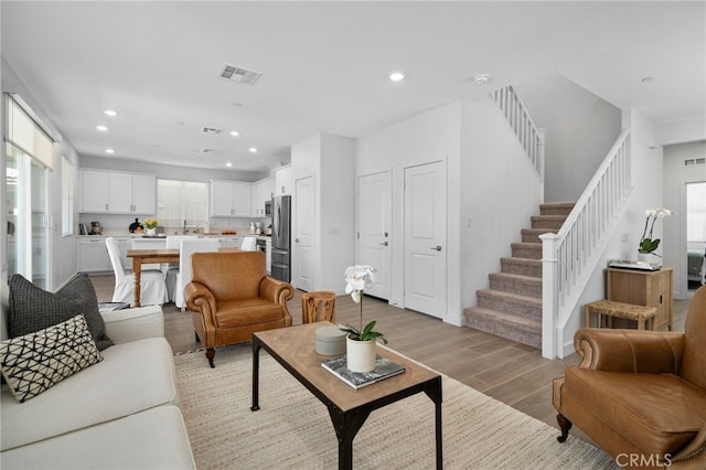 living area with light wood-style floors, visible vents, stairway, and recessed lighting