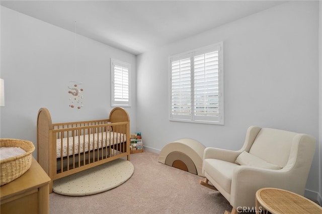 bedroom featuring a nursery area, baseboards, and carpet flooring