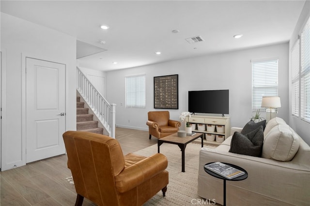 living room featuring recessed lighting, visible vents, light wood-style floors, baseboards, and stairs