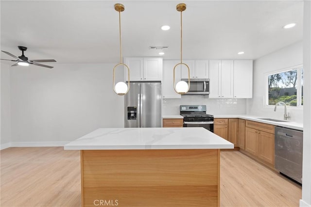 kitchen featuring stainless steel appliances, light wood finished floors, a sink, and decorative backsplash