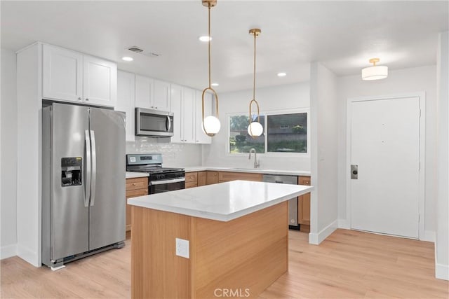 kitchen with stainless steel appliances, tasteful backsplash, visible vents, light wood-style flooring, and white cabinets