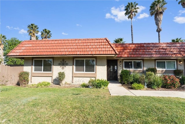 ranch-style home with stucco siding, a tiled roof, and a front yard