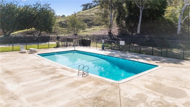 community pool featuring fence and a patio