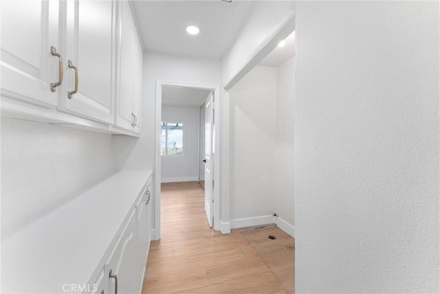 hallway with light wood-style flooring and baseboards