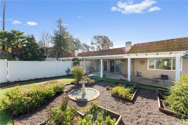 back of house with a patio, fence, a garden, and stucco siding